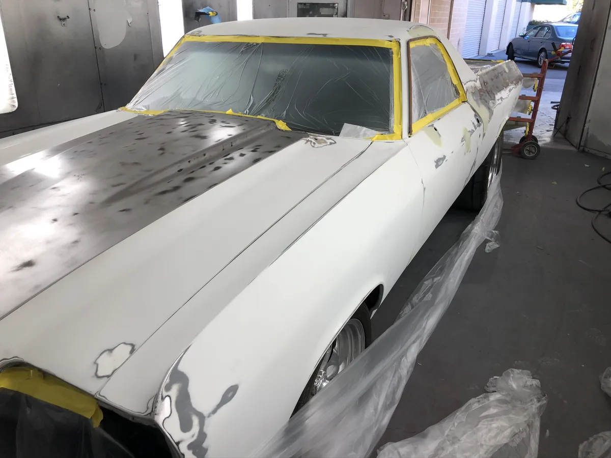 Classic car masked with primer in paint booth before refinishing